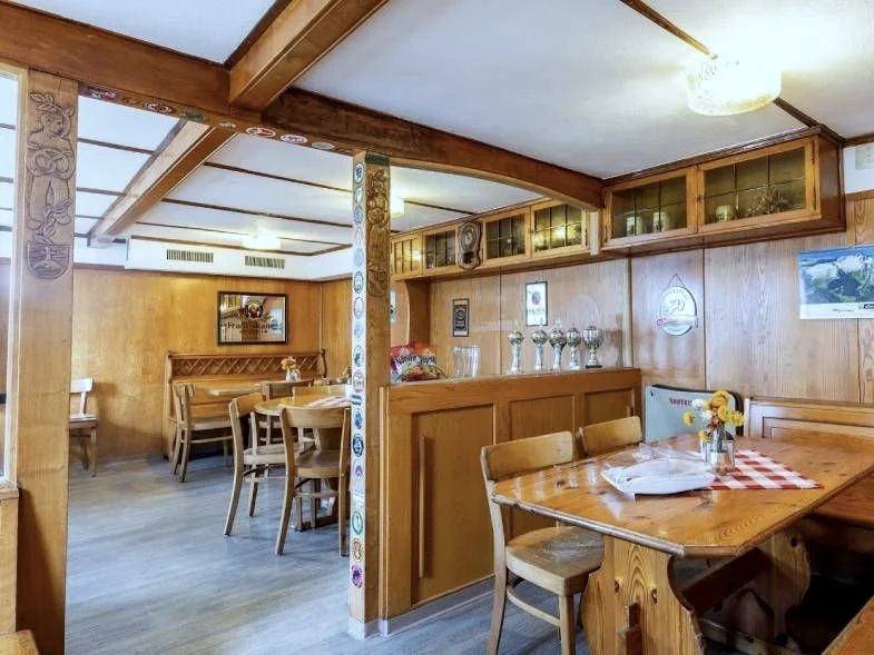 Gaststube im Restaurant Linde mit gemütlichen Holztischen und rot-weissen Tischdecken.