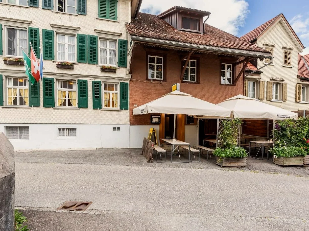 Aussenansicht des Restaurants Linde in Marbach mit Gartenwirtschaft und Sonnenschirmen.